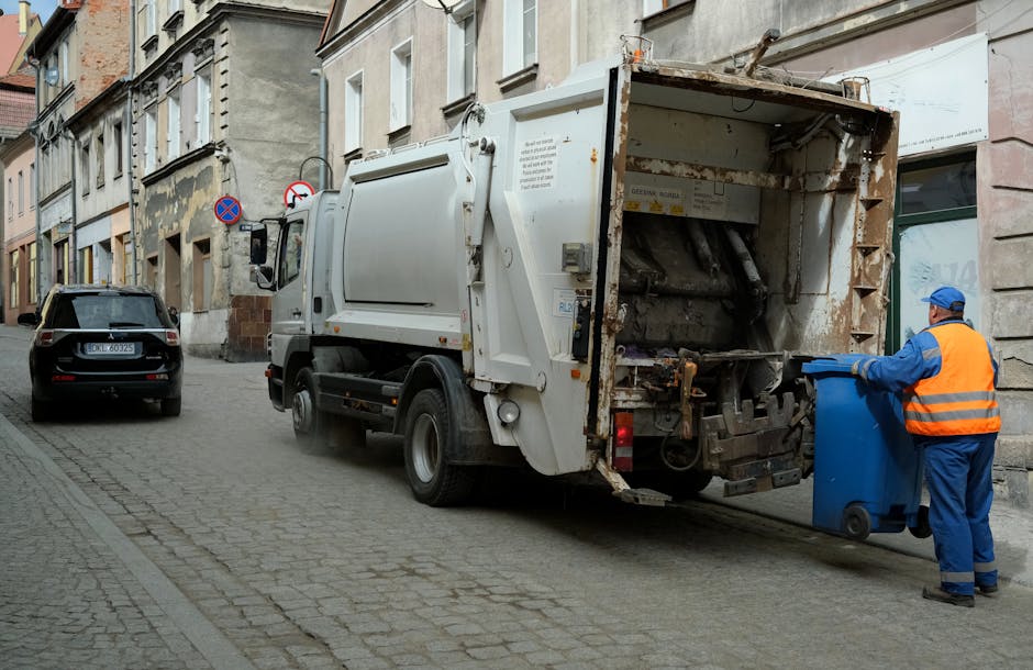A small, manually operated flatbed cart with metal frame and two large rubber wheels is loaded with various discarded items including cardboard boxes, plastic bags, and miscellaneous debris. The objec